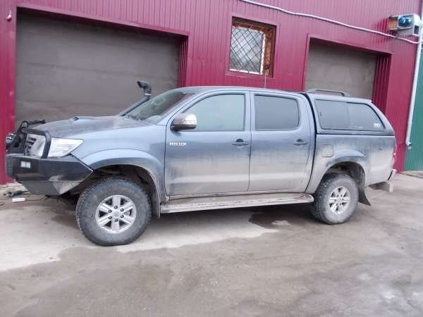 Toyota Hilux с кунгом сбоку у гаража